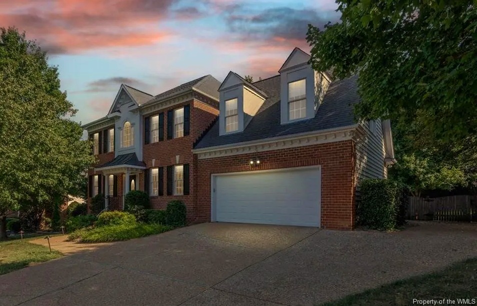 A two-story brick house with a two-car garage at sunset